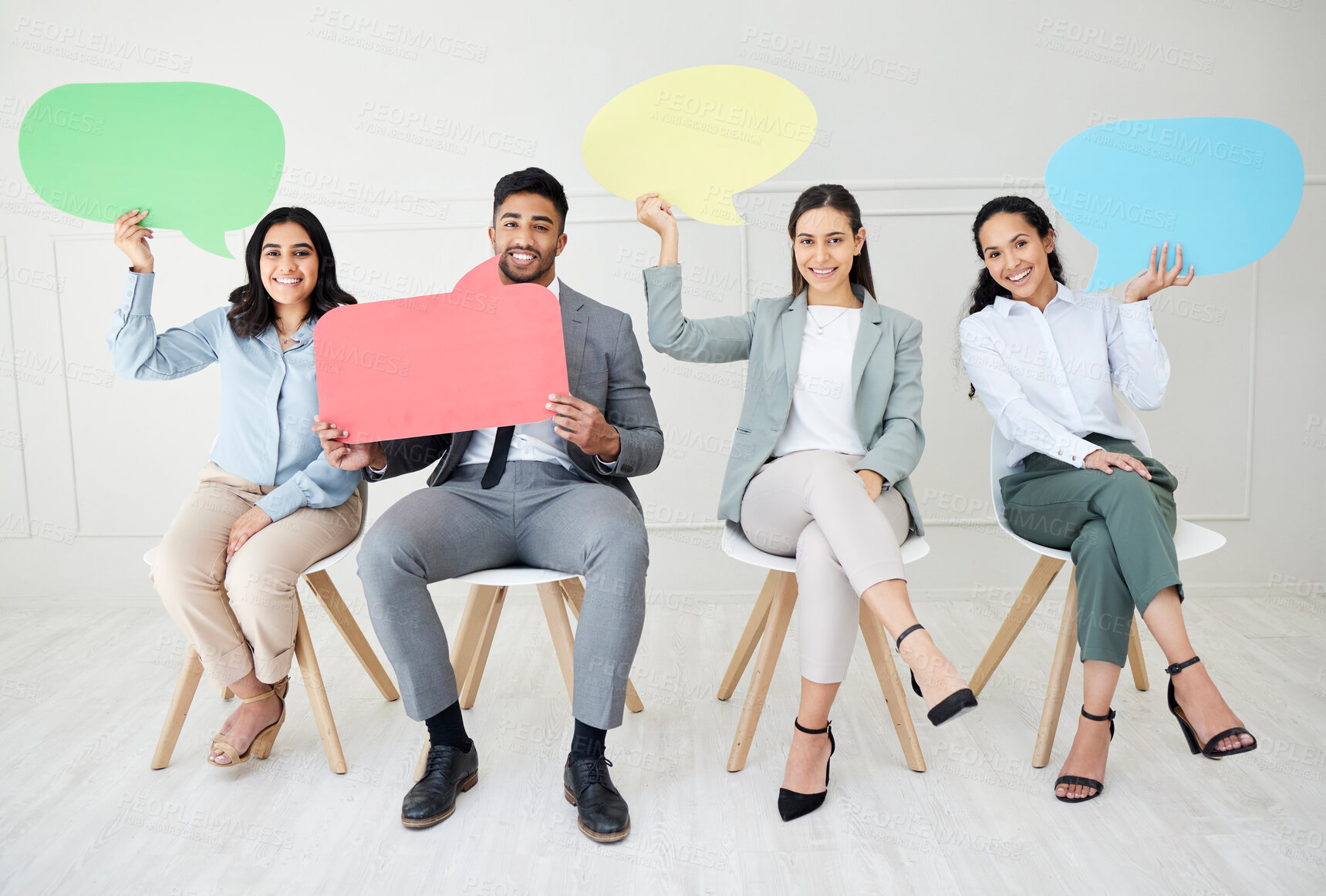 Buy stock photo Portrait of a group of businesspeople holding speech bubbles while sitting in line against a grey background