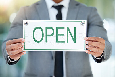 Buy stock photo Cropped shot of an unrecognizable businessman holding up an open sign while standing in the office