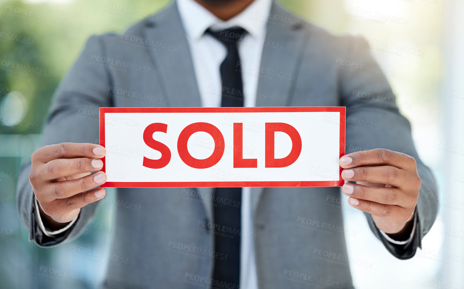 Buy stock photo Cropped shot of an unrecognizable businessman holding up a sold sign while standing in the office