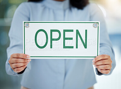 Buy stock photo Cropped shot of an unrecognizable businesswoman holding up an open sign while standing in the office