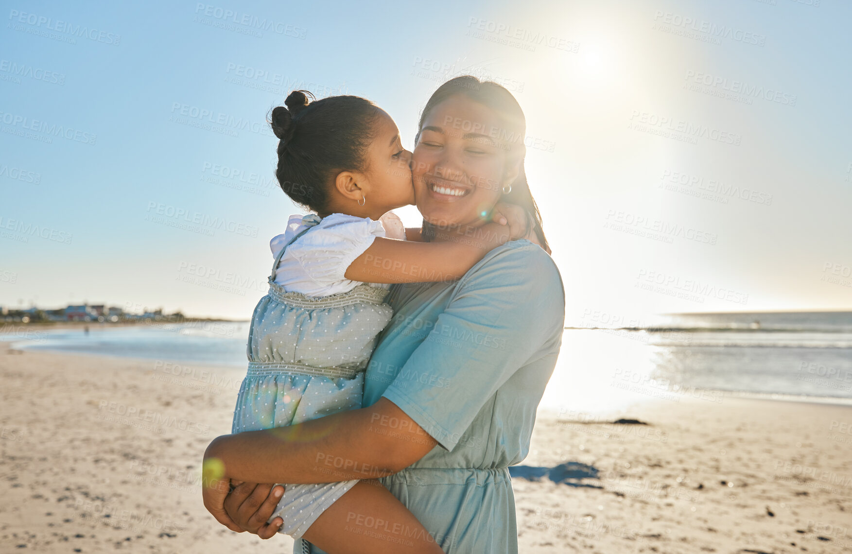 Buy stock photo Kiss, cheek and mom with child at beach for bonding on summer holiday, vacation and weekend by ocean. Sunshine, family and happy mother with young girl for relationship, affection and relax outdoors