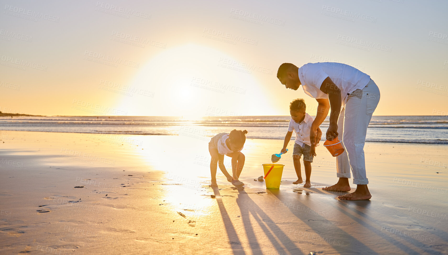 Buy stock photo Shot of a beautiful family bonding while spending a day at the beach together