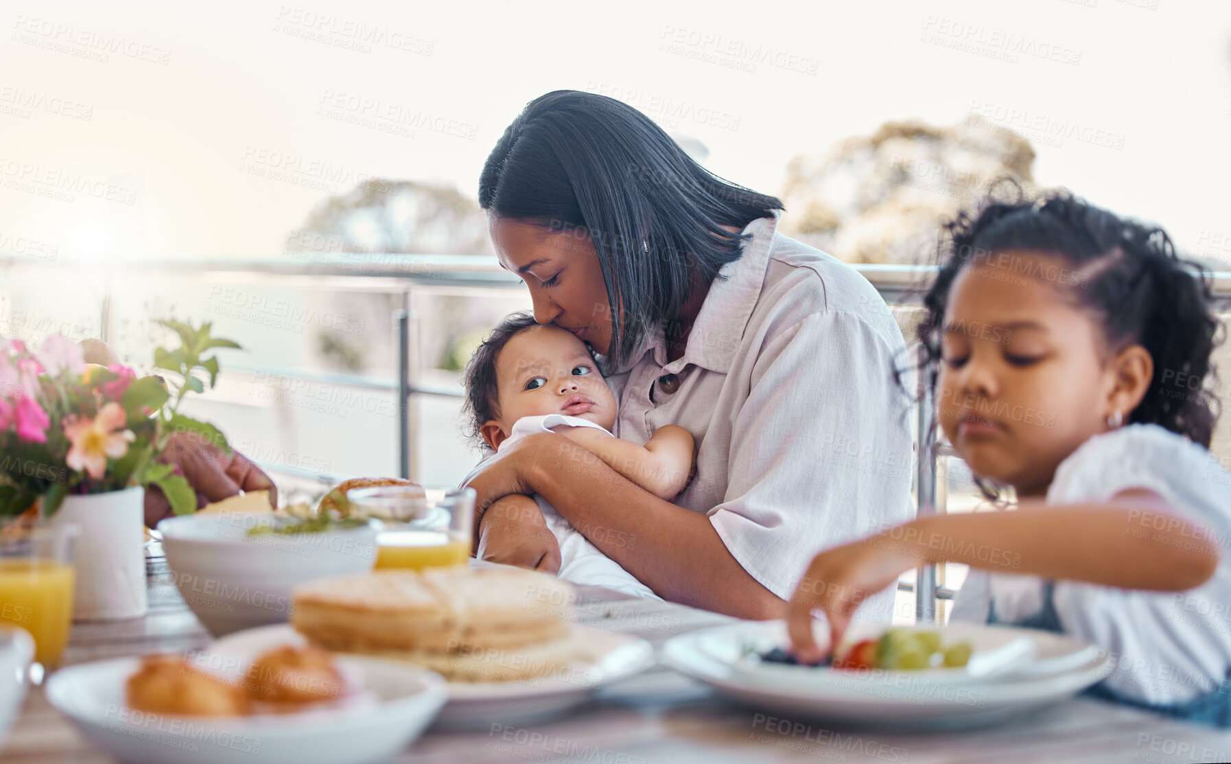 Buy stock photo Kiss, mom and kids at table for breakfast with care, eating and morning bonding together on balcony. Embrace, mother and children with food, love and happy family in home for weekend brunch on patio