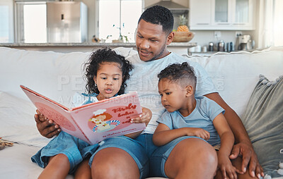 Buy stock photo Shot of a young man reading to his kids on the sofa at home