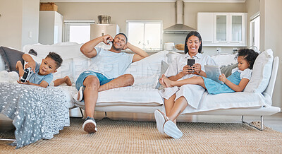 Buy stock photo Shot of a young family sitting together using different devices