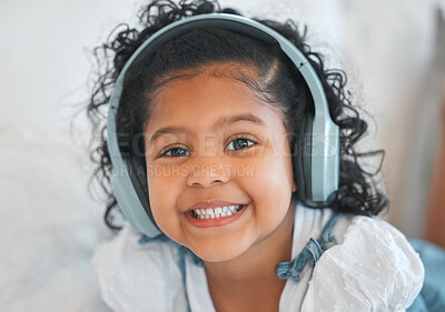 Buy stock photo Shot of an adorable little girl using headphones while relaxing on the sofa at home