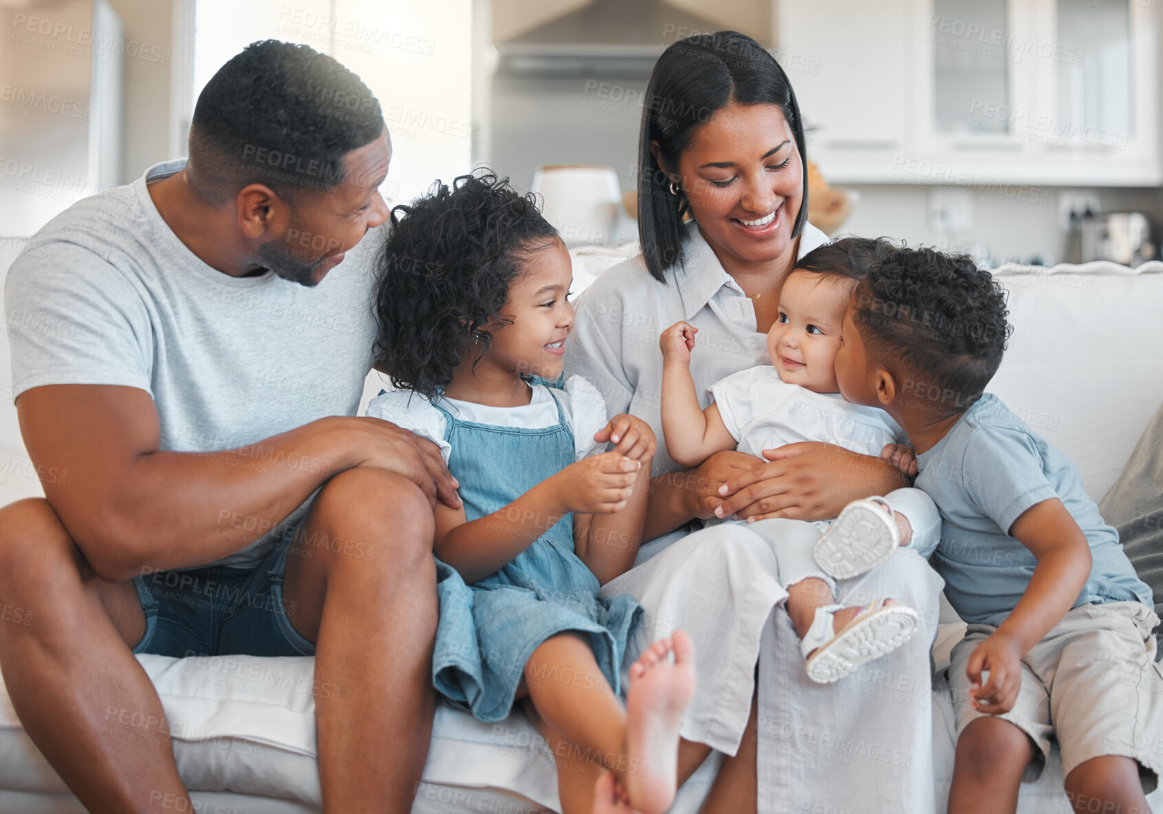 Buy stock photo Shot of a young family happily bonding together on the sofa at home