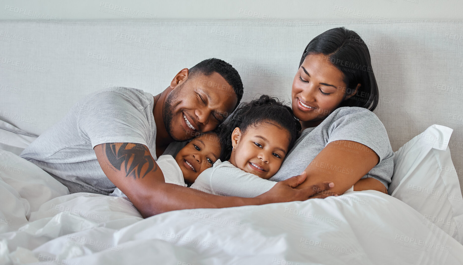 Buy stock photo Family, happy and parents hug in bed with children for bonding, love and fun at home. Man, woman and kids care with girl and boy in bedroom for relax, weekend rest and smile together in morning