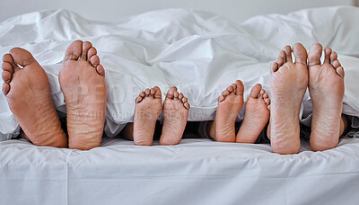 Buy stock photo Shot of a family laying barefoot on a bed at home