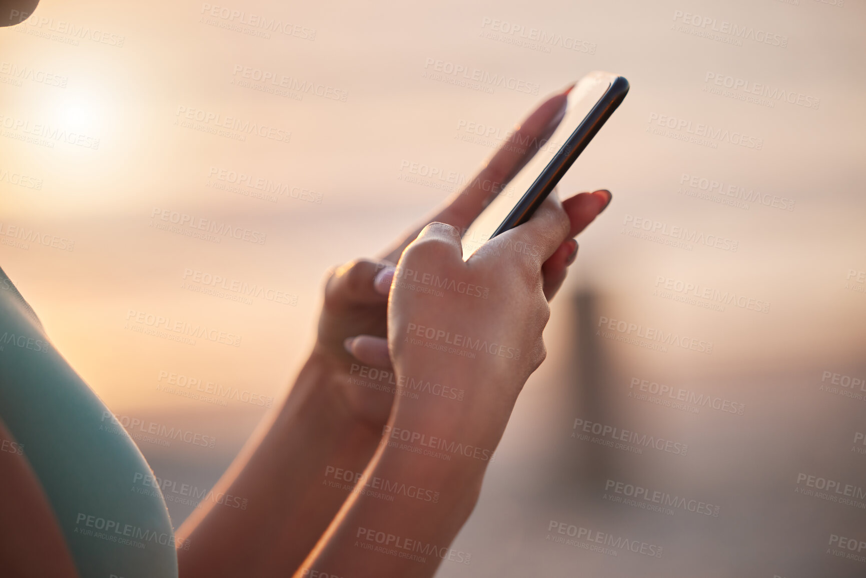 Buy stock photo Shot of an unrecognizable woman using her cellphone at the beach