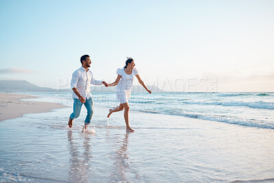 Buy stock photo Shot of a young couple running on the beach