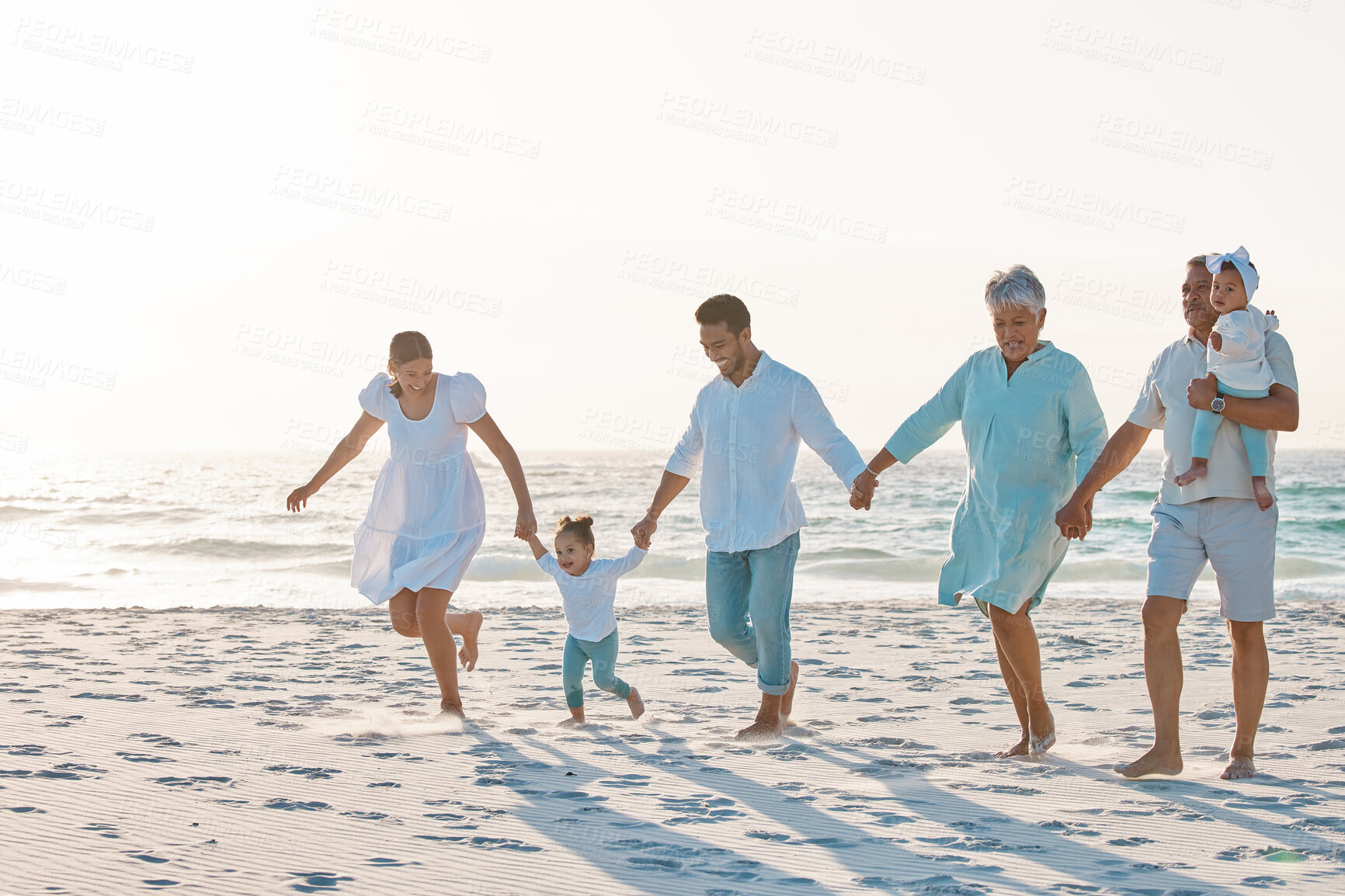 Buy stock photo Big family, holding hands and walking on beach for holiday weekend or vacation with mockup space. Grandparents, parents and kids on a ocean walk together for fun bonding or quality time in nature