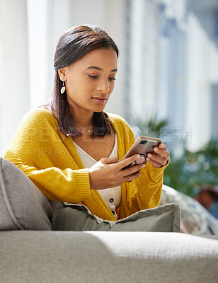 Buy stock photo Shot of a young woman using a phone at home