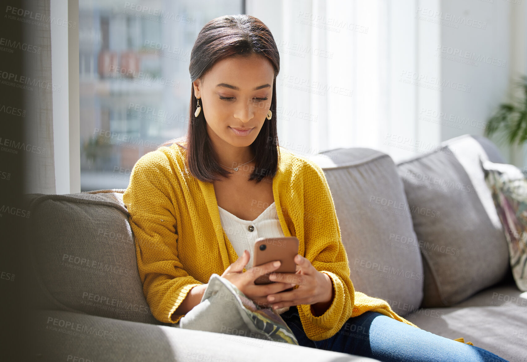 Buy stock photo Shot of a young woman using a phone at home