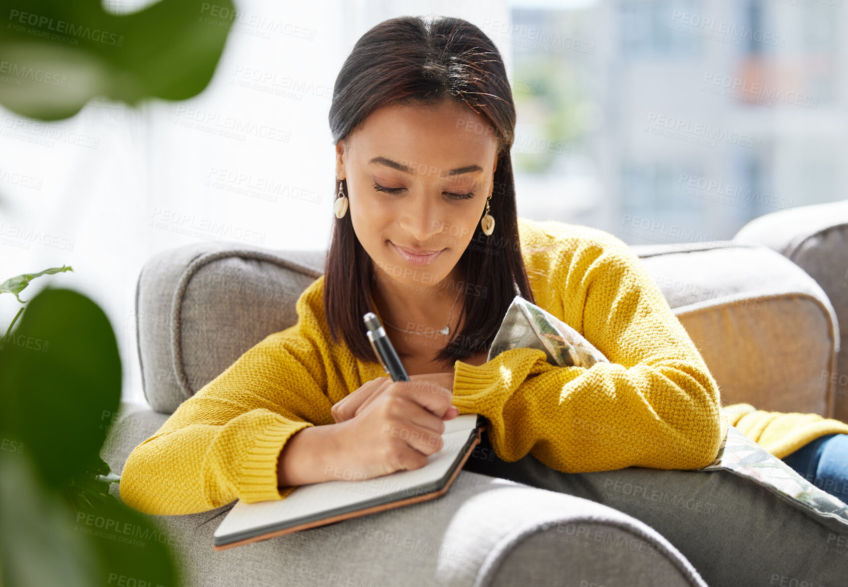 Buy stock photo Shot of a young woman writing in a diary at home