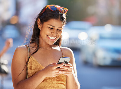 Buy stock photo Cropped shot of an attractive young woman checking her messages while out on the town