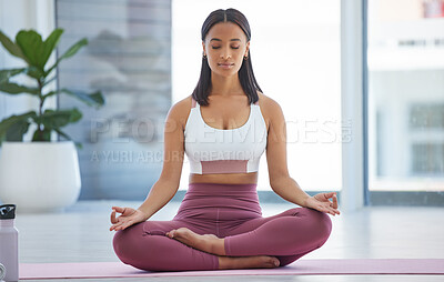 Buy stock photo Shot of a sporty young woman meditating while exercising in a yoga studio