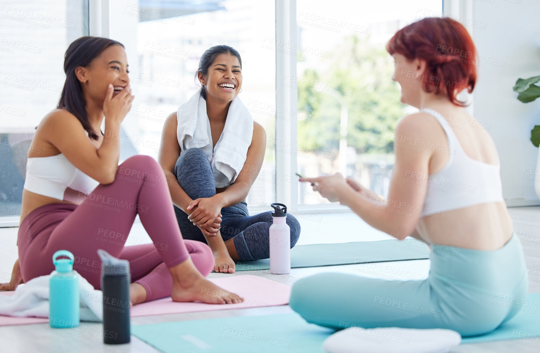 Buy stock photo Shot of a group of sporty young women taking a break while exercising in a yoga studio