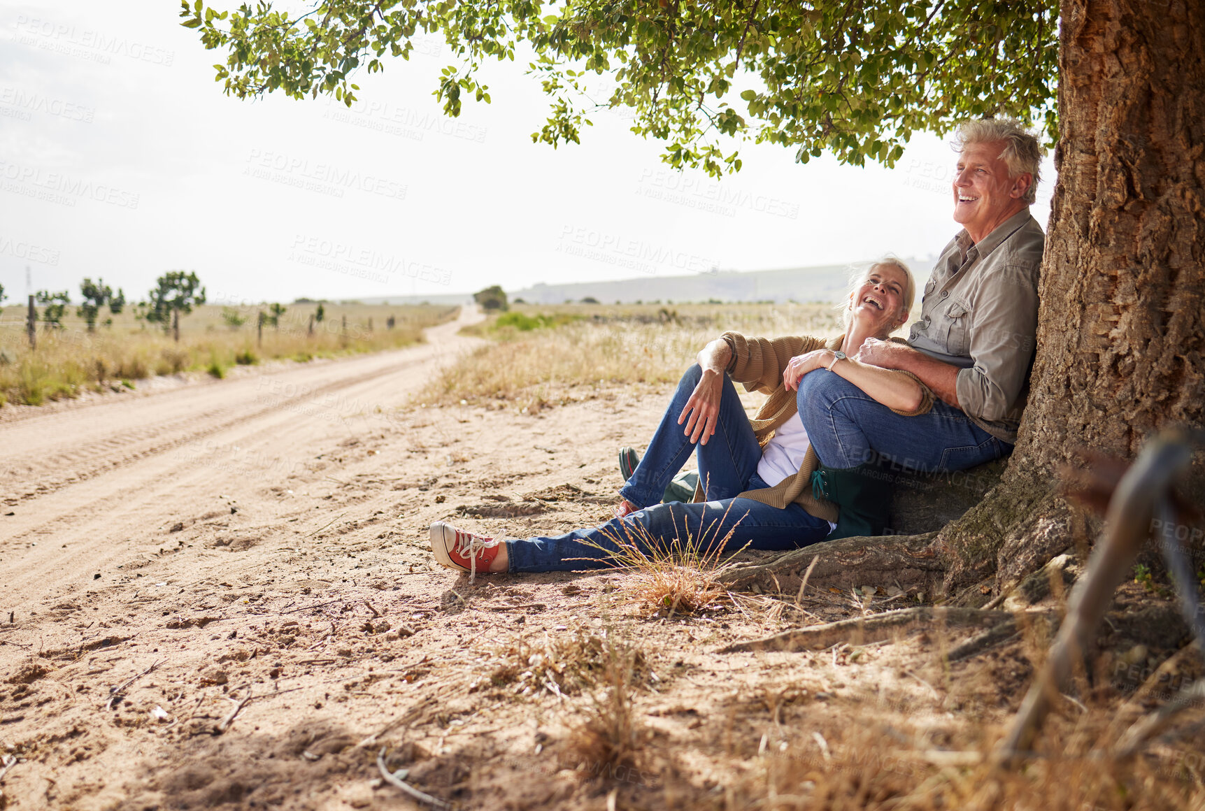 Buy stock photo Laugh, senior couple and together on farm, outdoor and tree in countryside for relaxing and bonding. Mature man, woman and farmers with smile for retirement, nature or environment for rural land rest