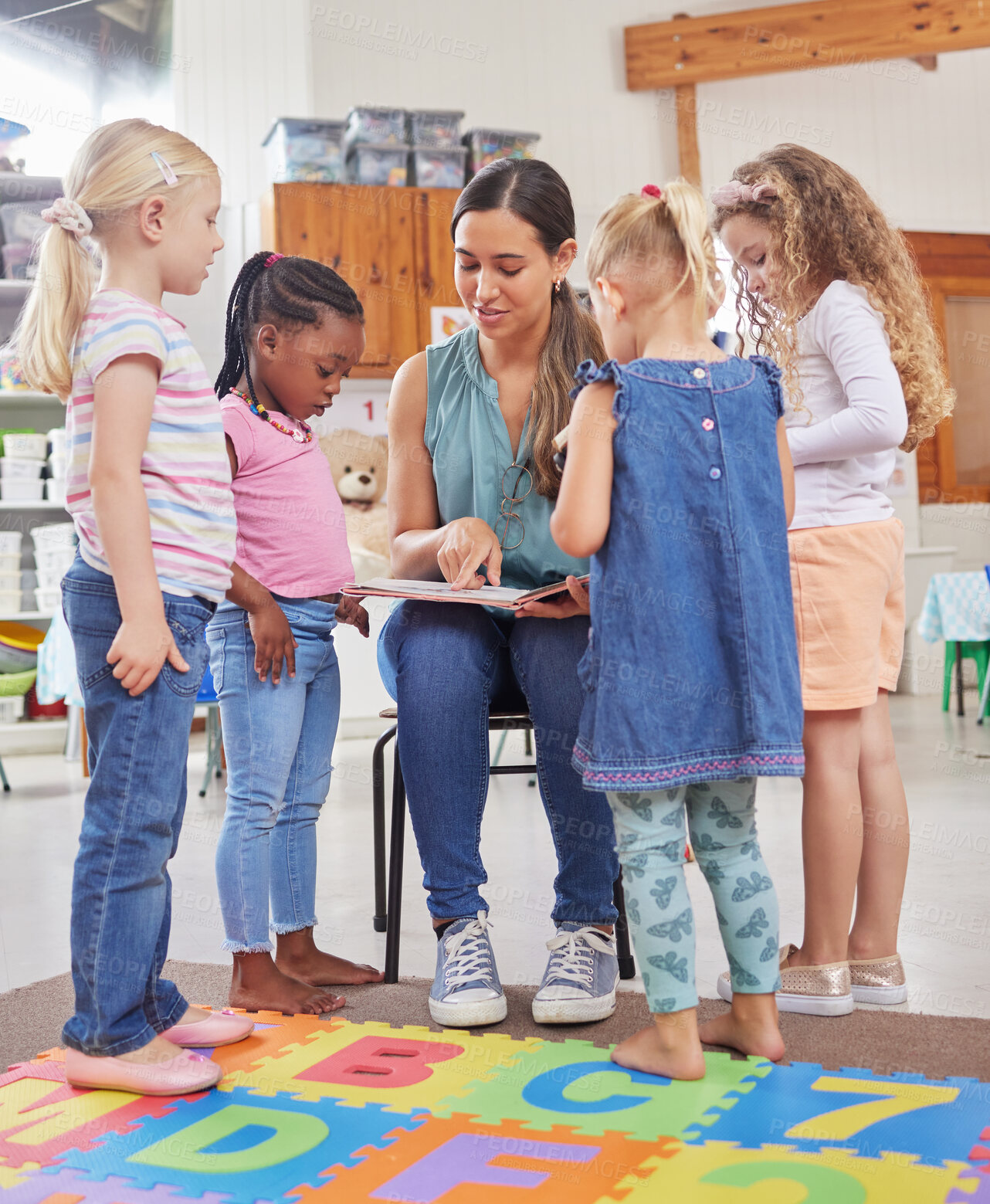 Buy stock photo Shot of a young woman reading to her preschool students