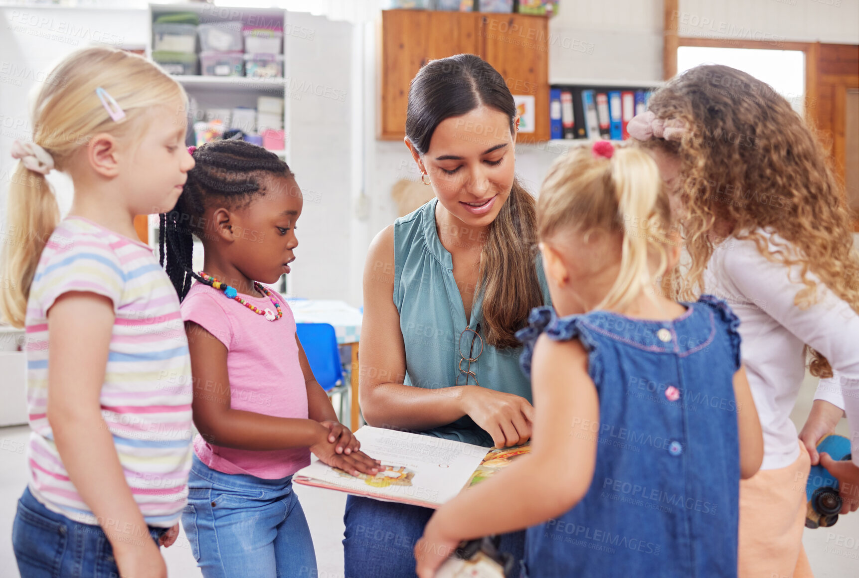 Buy stock photo Shot of a young woman reading to her preschool students