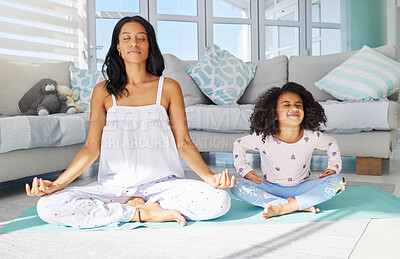 Buy stock photo Shot of a young mother and daughter meditating together at home