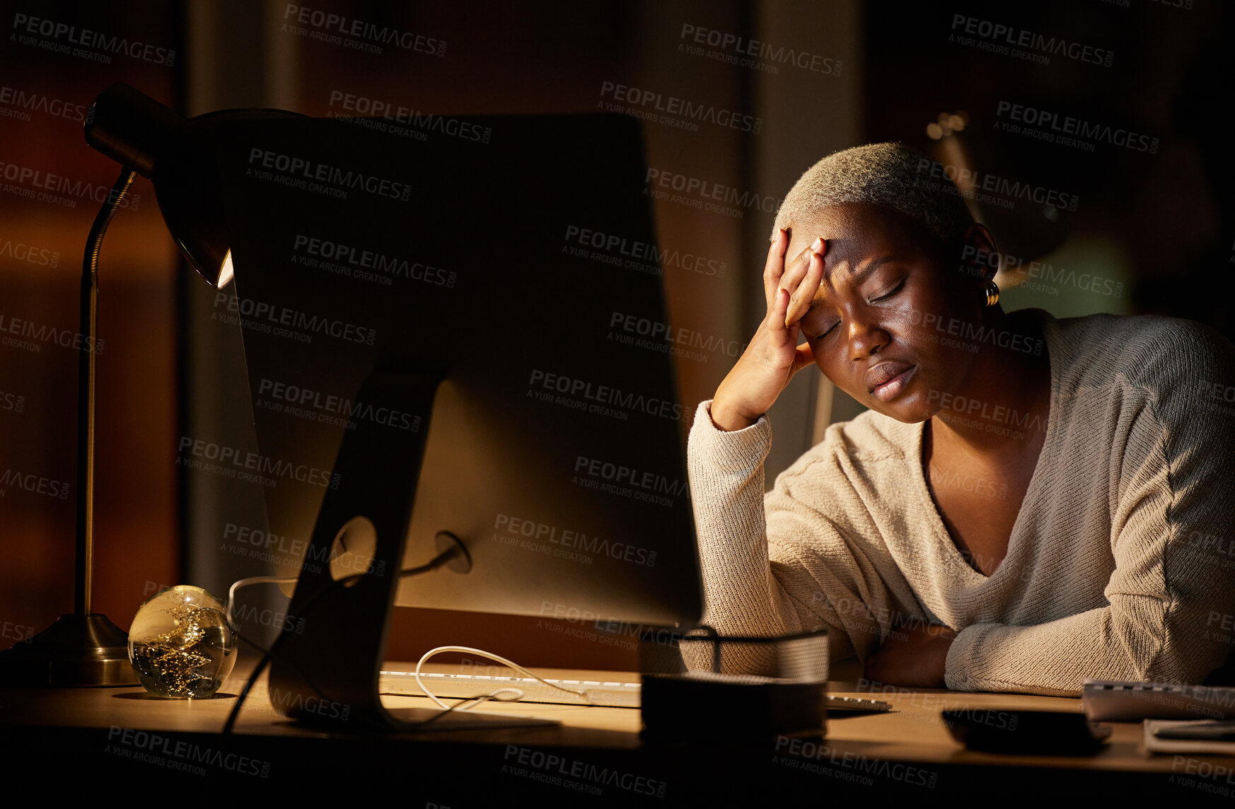 Buy stock photo Shot of a young businesswoman looking stressed out while working on a computer in an office at night