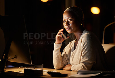Buy stock photo Shot of a young businesswoman talking on a cellphone while working on a computer in an office at night