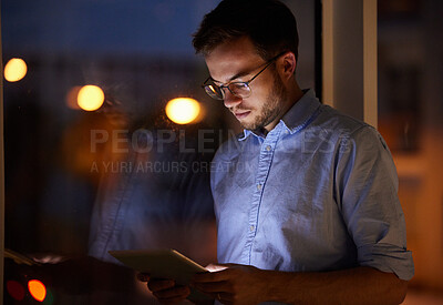 Buy stock photo Shot of a young businessman using a digital tablet in an office at night