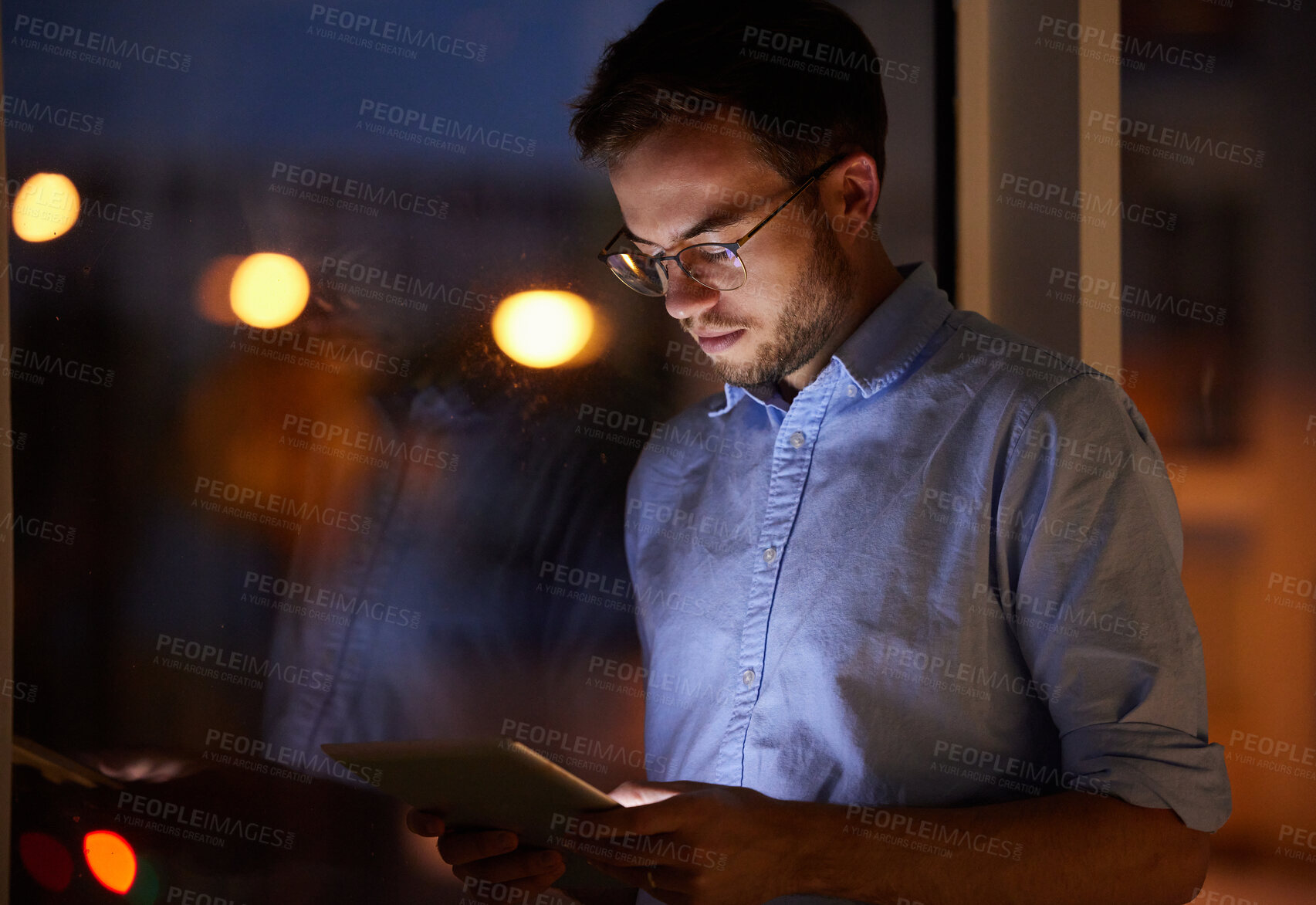 Buy stock photo Shot of a young businessman using a digital tablet in an office at night