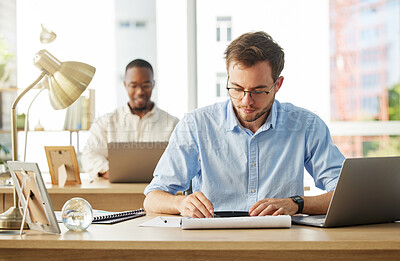 Buy stock photo Shot of a young male businessman working on his finances