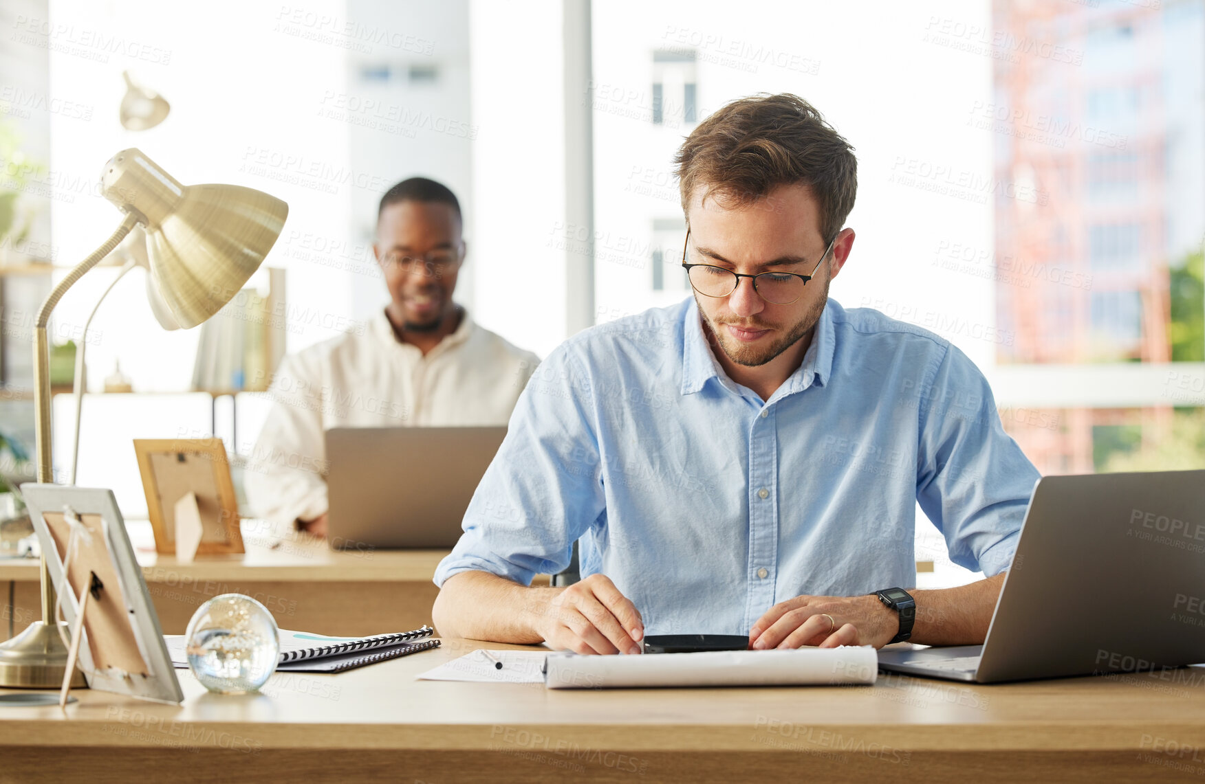 Buy stock photo Shot of a young male businessman working on his finances