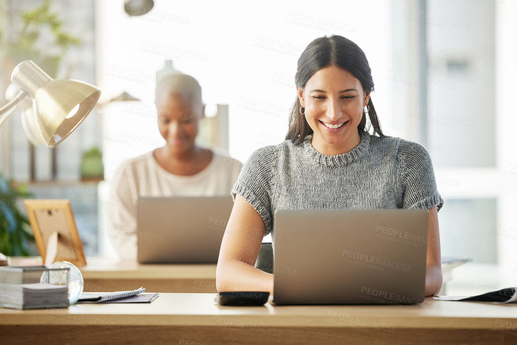 Buy stock photo Shot of two businesswomen working together in their office