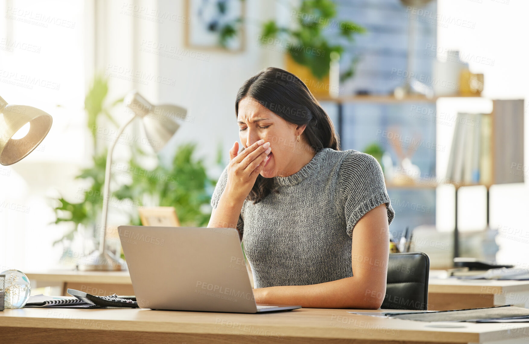 Buy stock photo Shot of a young businesswoman yawning at her desk