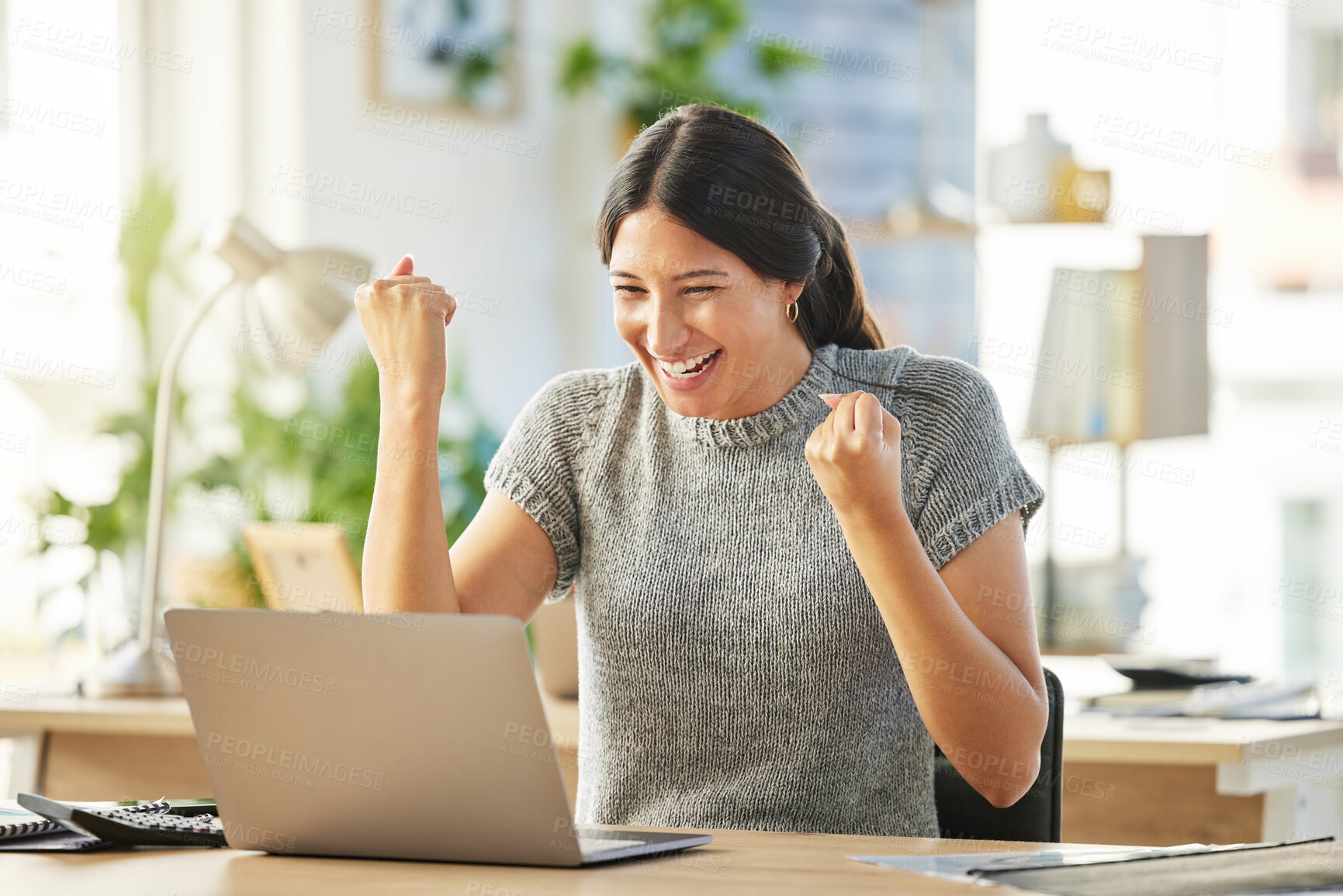 Buy stock photo Shot of a young businesswoman cheering in excitement at her desk