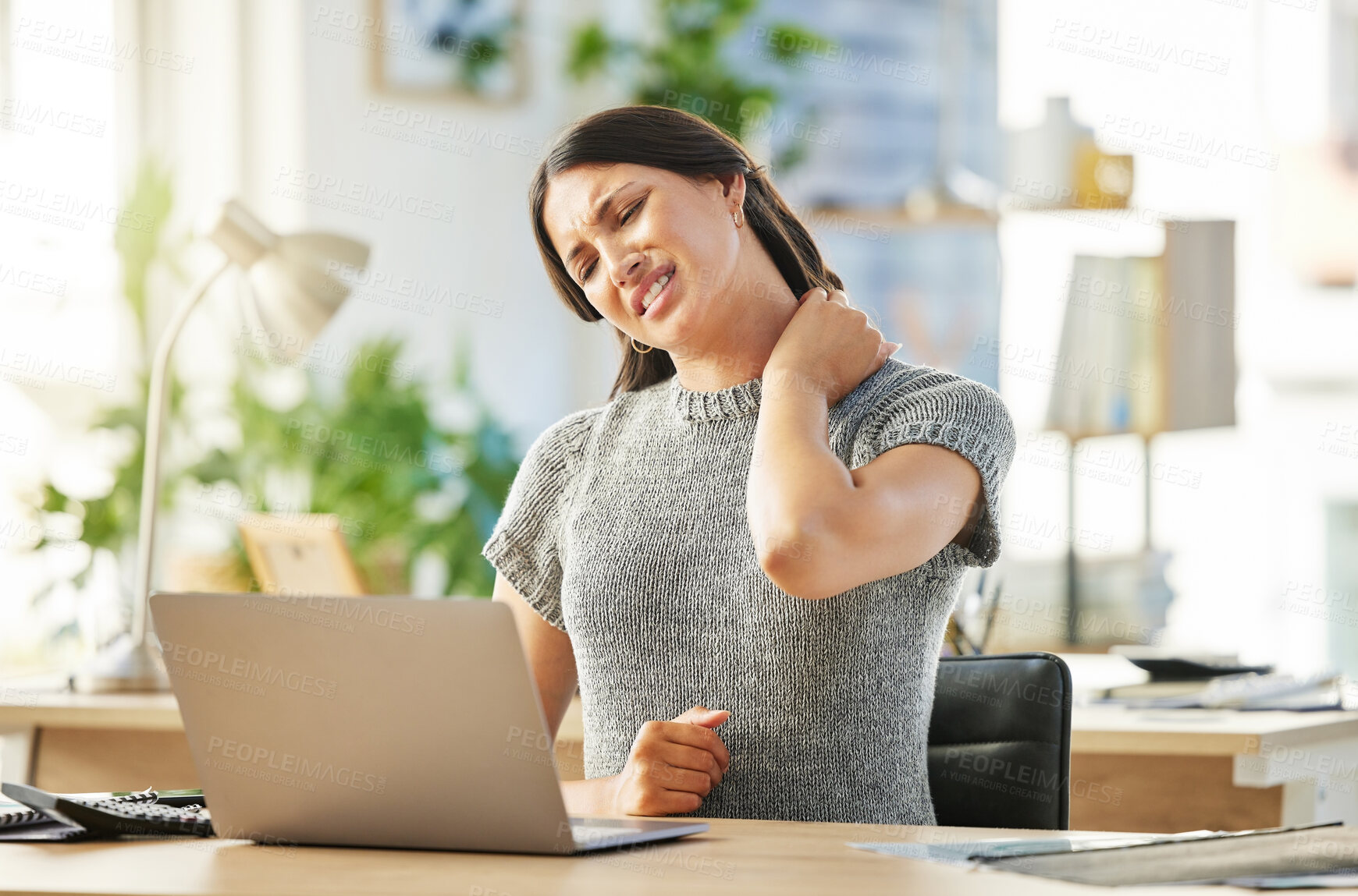 Buy stock photo Shot of a young businesswoman massaging a neck cramp while at her desk