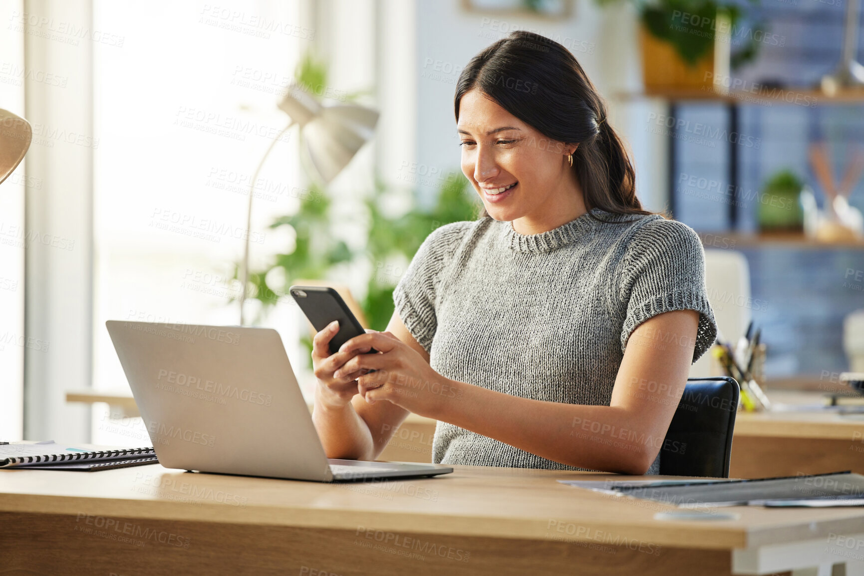 Buy stock photo Shot of a young businesswoman using her smartphone to send a text message