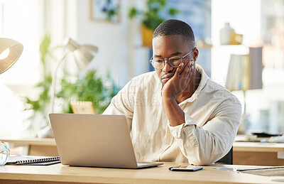 Buy stock photo Shot of a young businessman looking bored while sitting at his desk