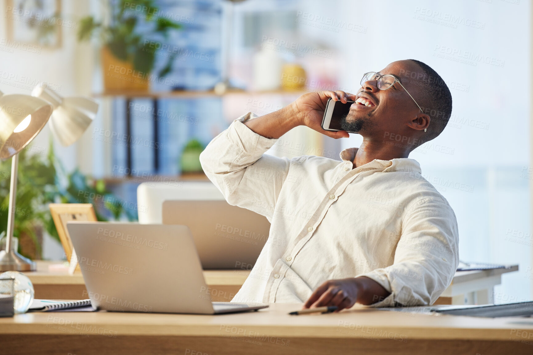 Buy stock photo Happy African business man, phone call and laugh with contact, comic conversation and talking at desk. Young black businessman, communication expert or crm with smartphone, happiness and connectivity