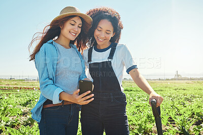 Buy stock photo Shot of two female farmers looking a cellphone while harvesting