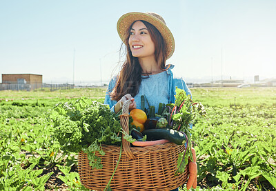 Buy stock photo Shot of a young farmer holding a basket of freshly harvested veggies