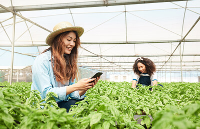 Buy stock photo Shot of a young woman using a cellphone while working on a farm