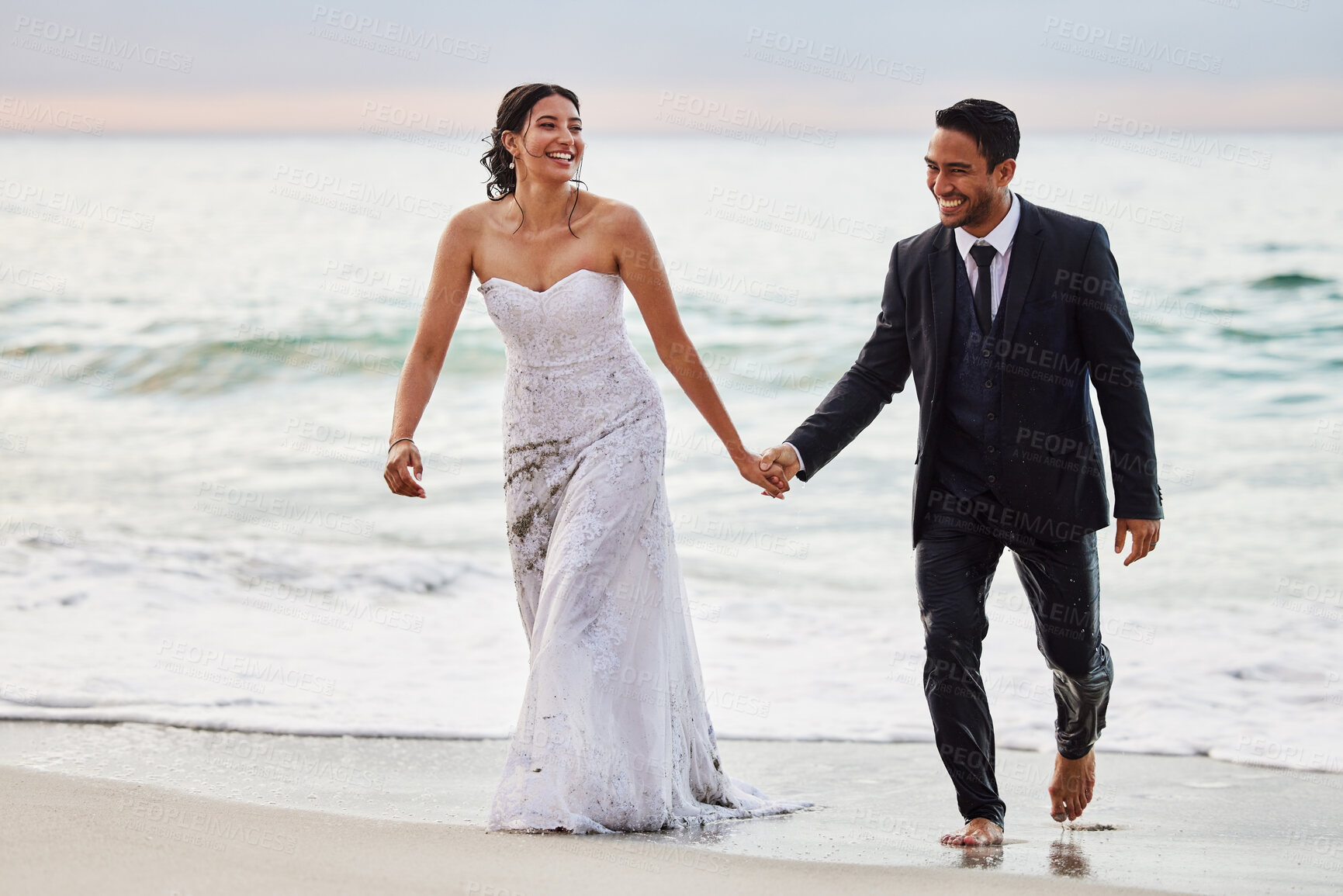 Buy stock photo Shot of a young couple on the beach on their wedding day