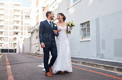 Buy stock photo Shot of a beautiful couple walking in the city on their wedding day