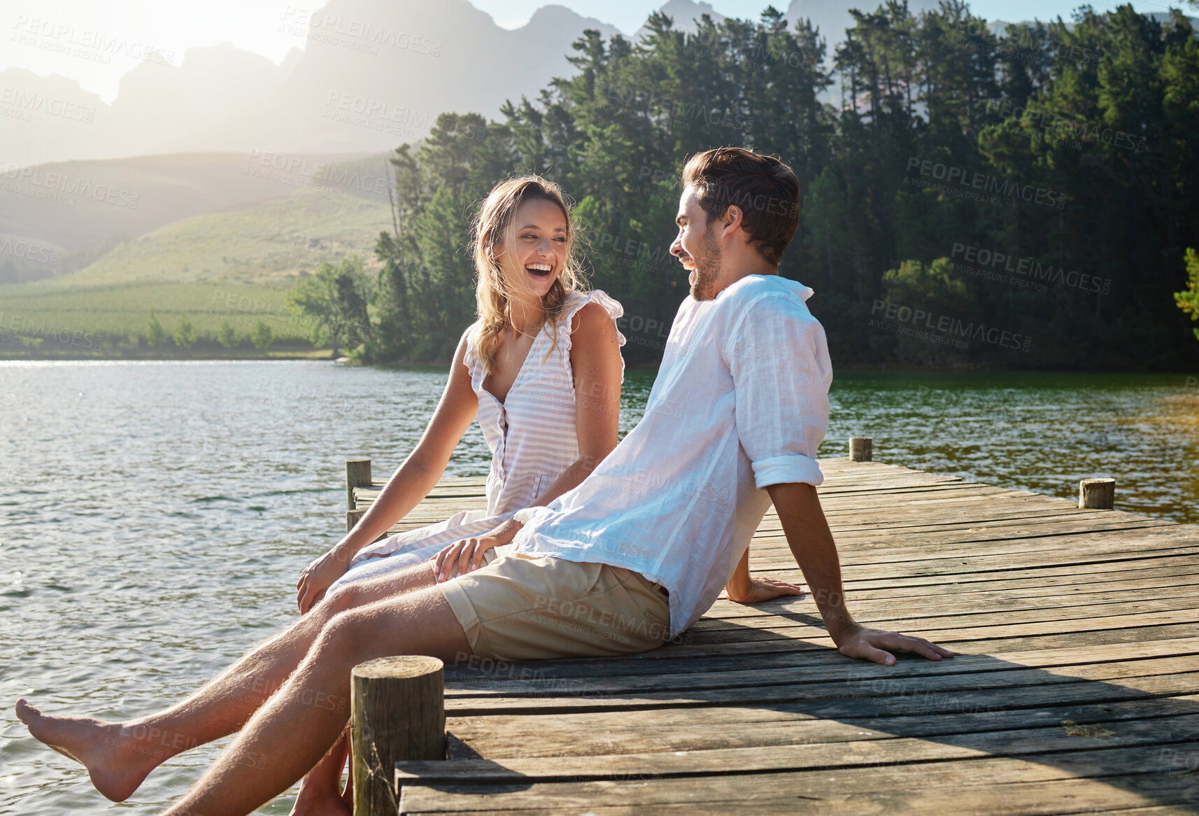 Buy stock photo Love, laugh and pier with couple at lake for bonding, romance and affectionate date. Nature, travel and holiday with man and woman sitting on boardwalk in countryside for happy, summer and vacation