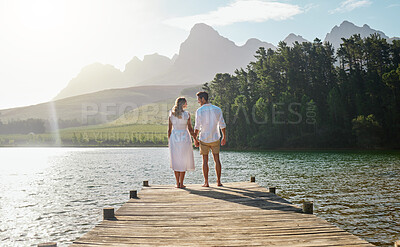 Buy stock photo Love, couple and holding hands at lake, smile and bonding  outdoors on vacation sunrise. Romance date, care and happy man and woman with trust, support or affection for romantic holiday at creek pier