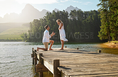 Buy stock photo Man, woman and engagement proposal by lake on vacation with surprise, wow or happiness in sunshine. Couple, marriage offer and ring in nature for romance, love and happy on holiday in summer by water