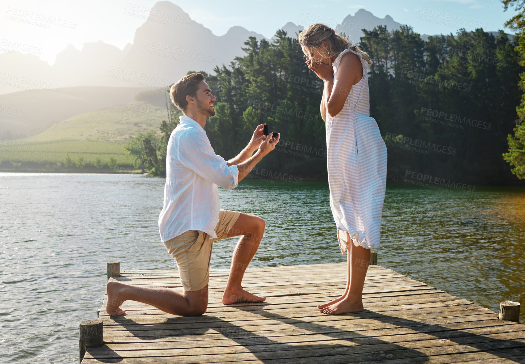 Buy stock photo Man, woman and marriage proposal by lake on vacation with surprise, wow or happiness in sunshine. Couple, engagement and offer ring in nature for romance, love and happy on holiday in summer by water