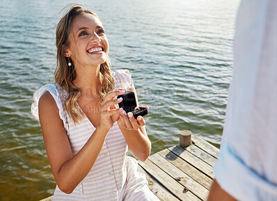 Buy stock photo Happy, love and a woman proposing to a man, getting engaged and showing a ring. Couple, excited and a young girl asking her boyfriend for marriage, kneeling to propose and ask a question by a lake