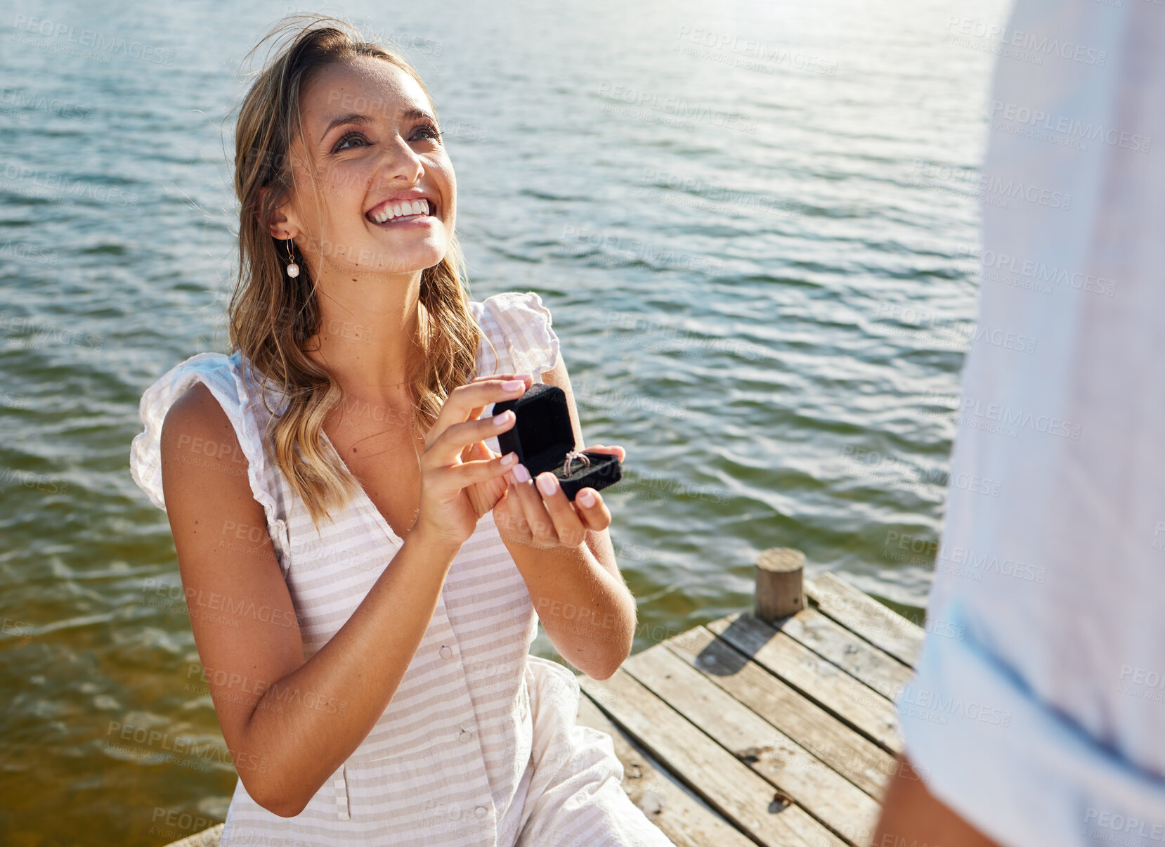 Buy stock photo Happy, love and a woman proposing to a man, getting engaged and showing a ring. Couple, excited and a young girl asking her boyfriend for marriage, kneeling to propose and ask a question by a lake